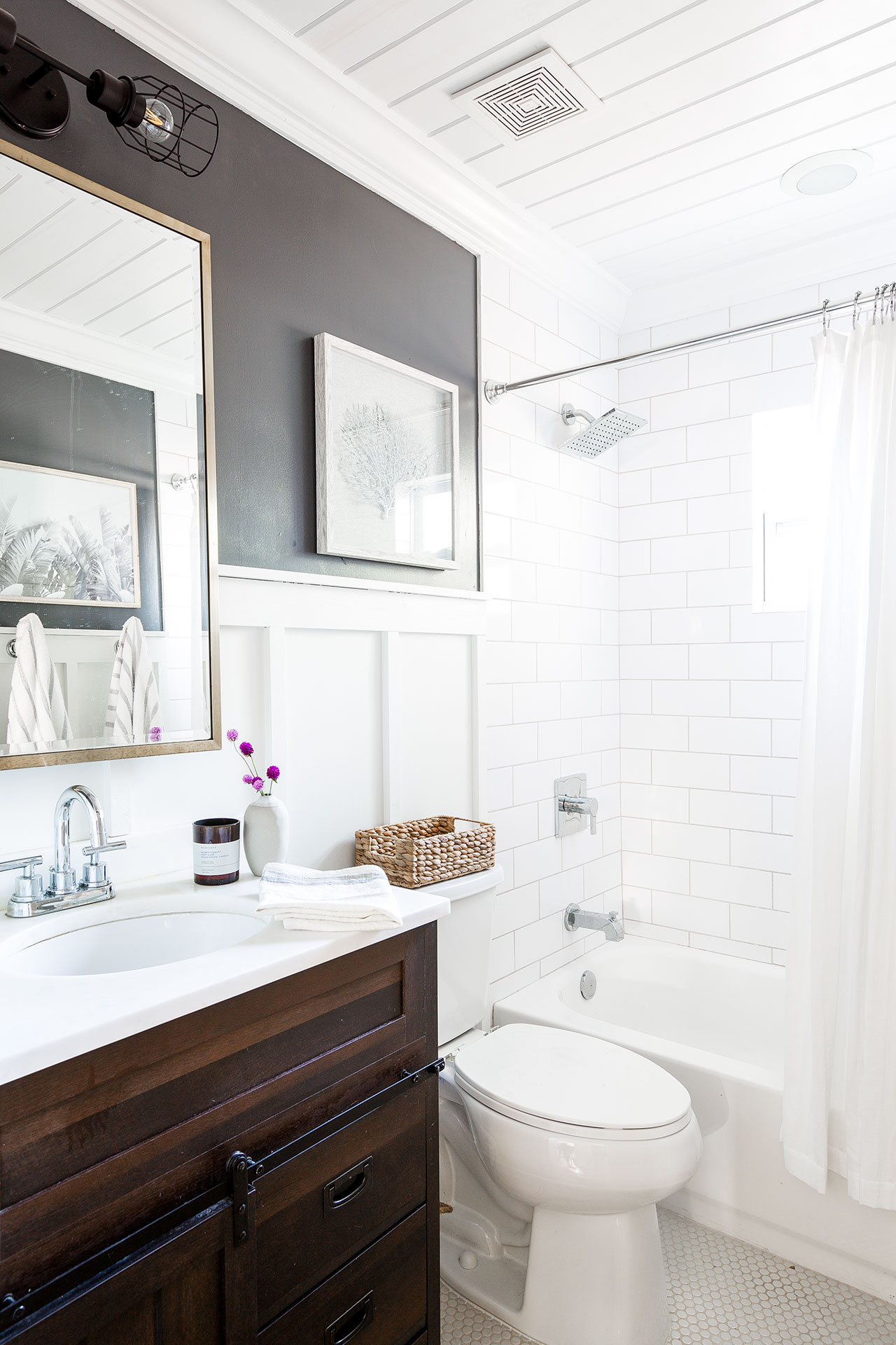 Beautiful interior design of the guest bathroom with a great amount of natural light, gorgeous white subway tiles, and complemented with a darker brown vanity.